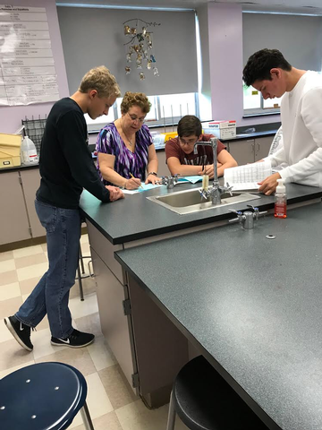 Chemistry teacher working with students in lab